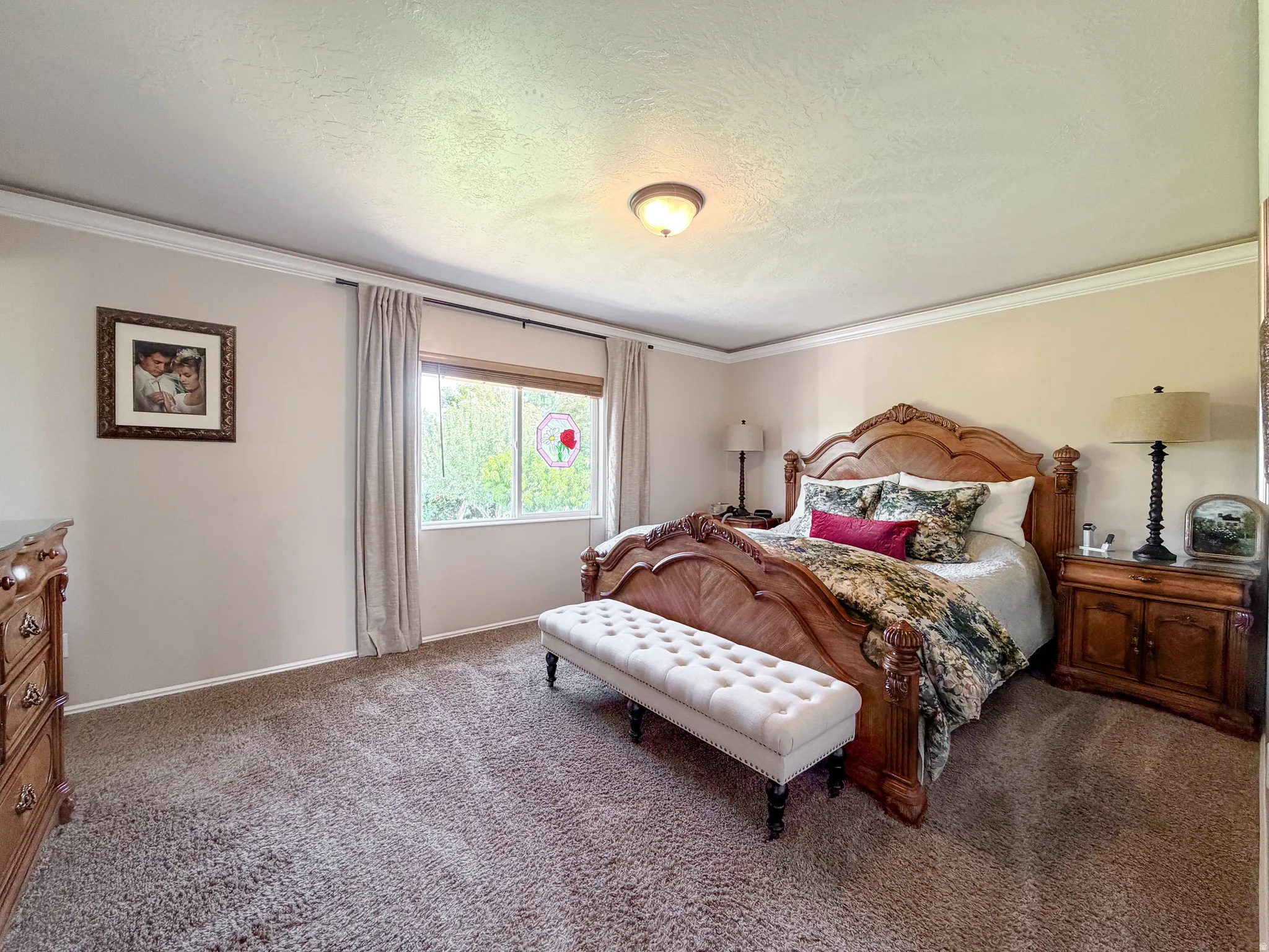 Wall-to-wall carpeting with crown molding, a large window, and an attached ceiling light fixture