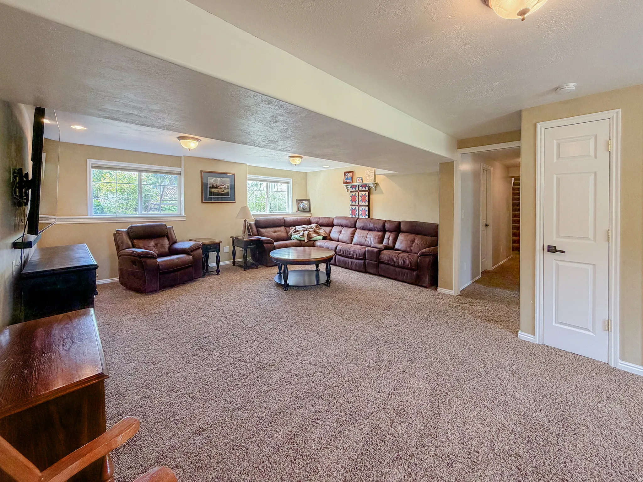 Generous room proportions with carpet flooring, recessed lighting, and multiple windows providing natural illumination