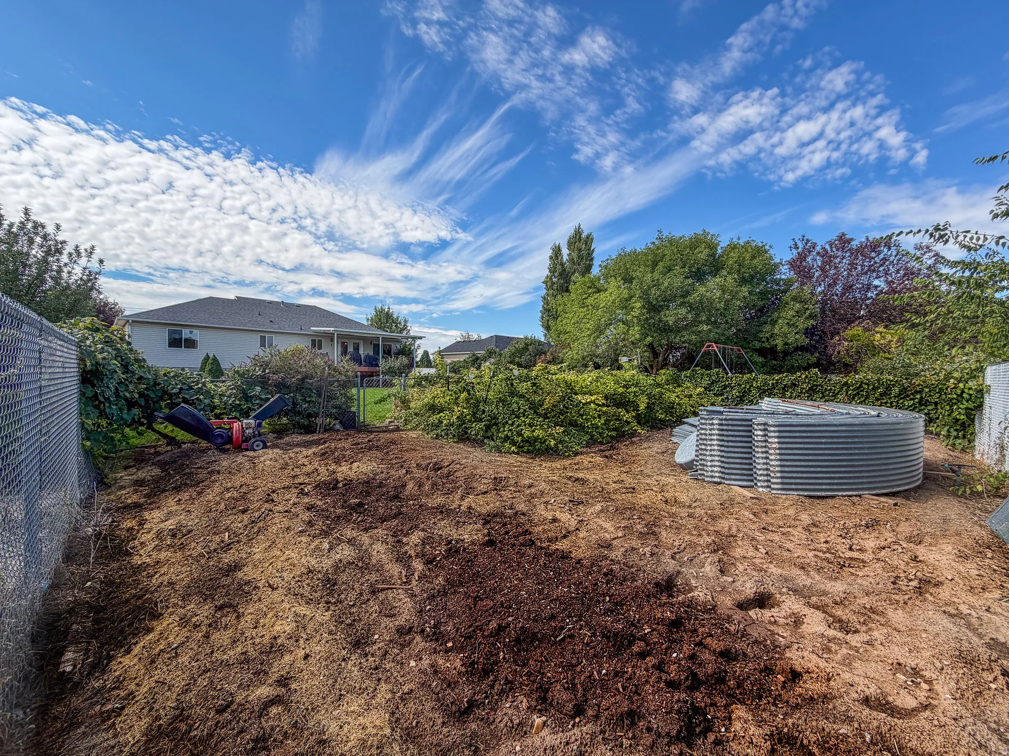 Expansive backyard space with chain-link fencing and a partially cleared area