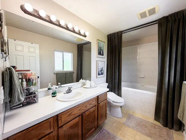 Wide vanity with wood-finish cabinetry, integrated sink, and laminate countertop