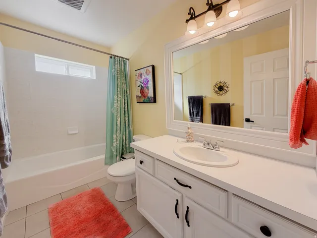 Bathroom featuring a white vanity with cabinet storage, integrated sink, and an expansive framed mirror