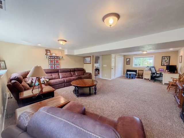 Carpeted living area with recessed lighting, a window, and two permanent doors