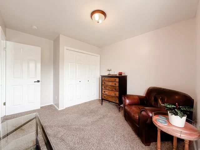 Wall-to-wall carpeting with light-toned walls, white paneled doors, and a built-in closet with bifold doors