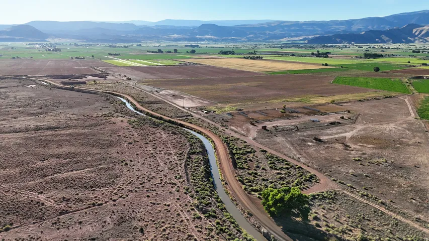 Expansive rural terrain featuring a winding irrigation canal and varied agricultural fields