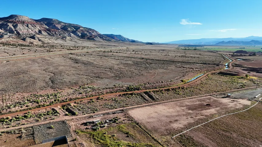 Expansive land parcel featuring desert terrain, a distant mountain range, and a visible irrigation canal