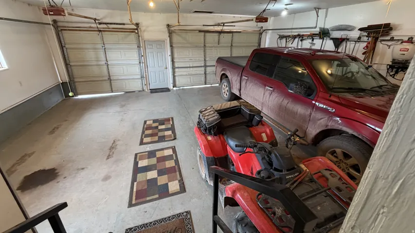Two garage doors, overhead lighting, concrete flooring, and a single window