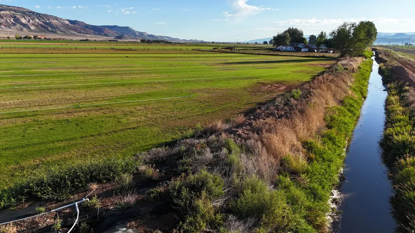 Expansive agricultural landscape featuring a water canal and distant mountain range