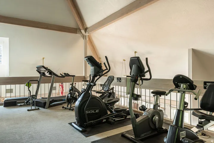 Dedicated fitness area featuring carpeted flooring and exposed wood beams