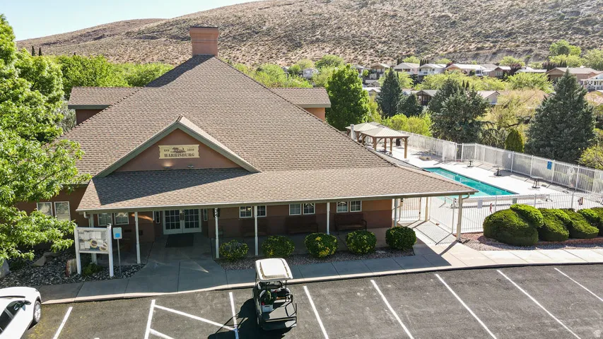 Building exterior with a prominent A-frame roofline, covered entrance, and an adjacent outdoor swimming pool area with a surrounding fence