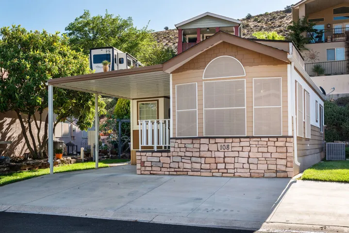 Stone veneer facade with an arched window and covered carport