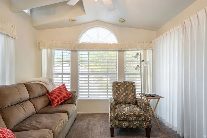 Vaulted ceiling with an integrated ceiling fan, multiple windows with blinds, and an arched transom window