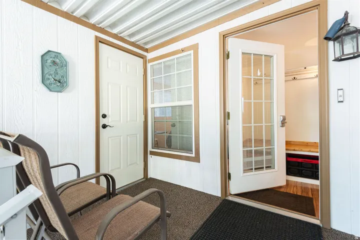 Enclosed porch with panel siding, a single-pane window with blinds, and a paneled entry door