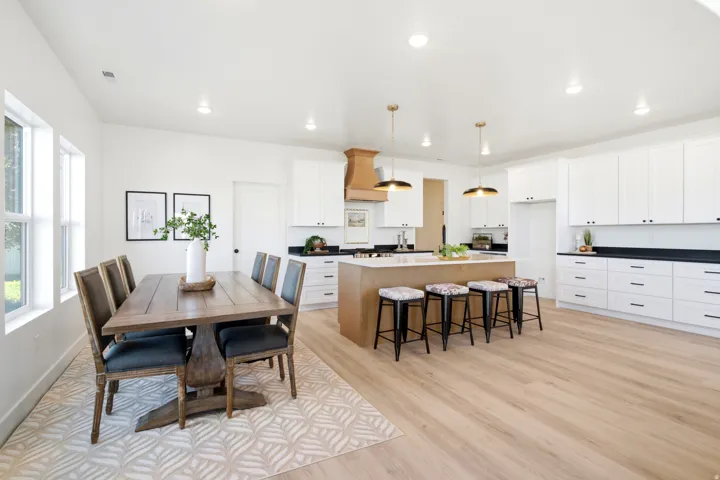 Open-concept living area with light wood-finish flooring, white cabinetry, a large kitchen island, and recessed lighting