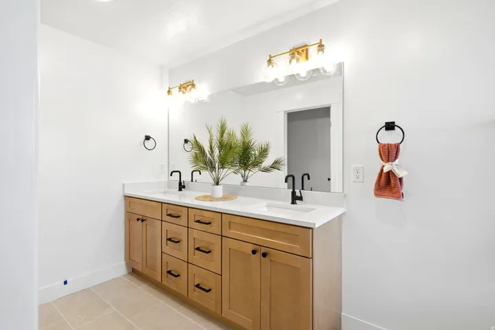 Dual vanity with light wood-finish cabinetry, white countertop, and matte black fixtures