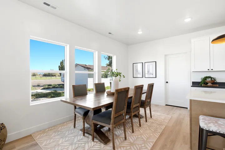Open-concept dining area with multiple windows, wood-finish flooring, and recessed lighting