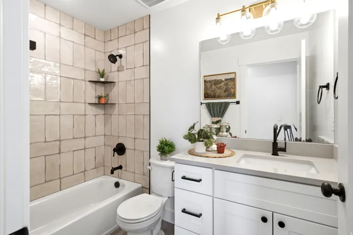 White vanity with dark hardware, quartz countertop, and integrated sink