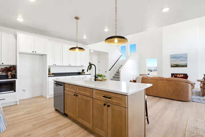 Spacious kitchen featuring white cabinetry, light wood-finish flooring, and a large center island with a white countertop