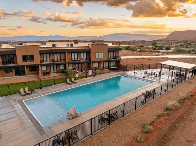Expansive outdoor swimming pool with surrounding patio space, a dedicated shaded seating area, and durable black perimeter fencing