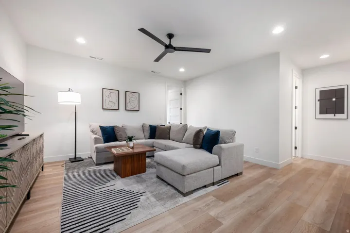 Recessed lighting, light wood-finish flooring, white walls, and a black ceiling fan