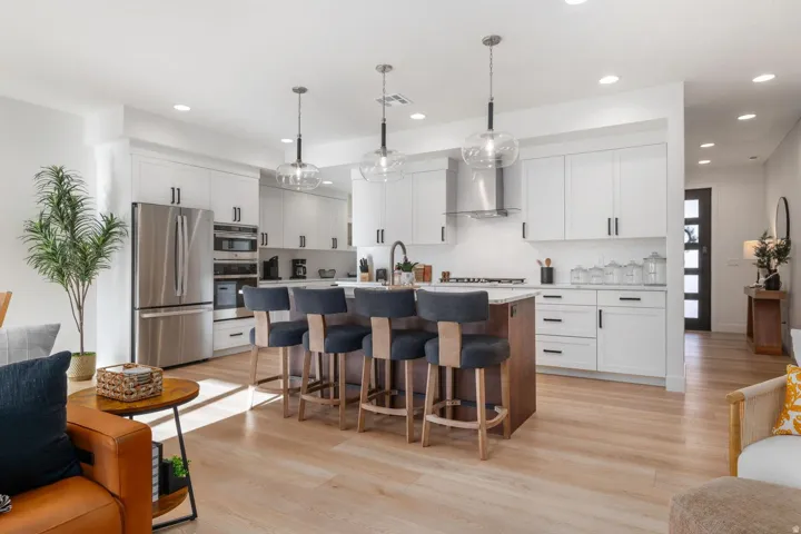 Kitchen featuring a center island with seating, white shaker-style cabinetry, stainless steel appliances, and light wood-finish flooring