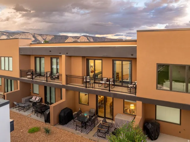 Multi-level stucco exterior with private balconies, ground-level patios, expansive windows, and mountain scenery