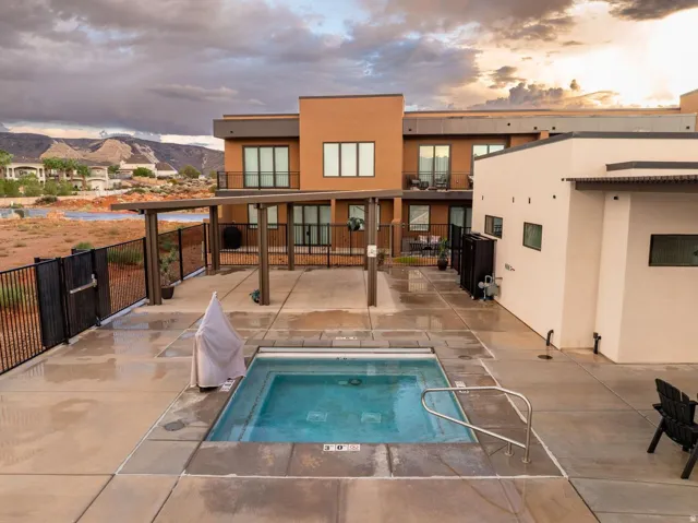 Expansive outdoor patio with concrete paving, a built-in spa, and a modern pergola structure