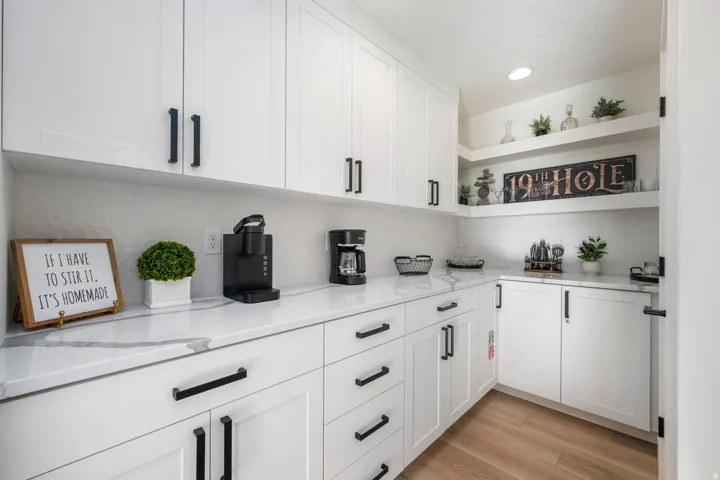 White cabinetry with black hardware, wood-finish flooring, white countertops, a tiled backsplash, and recessed lighting