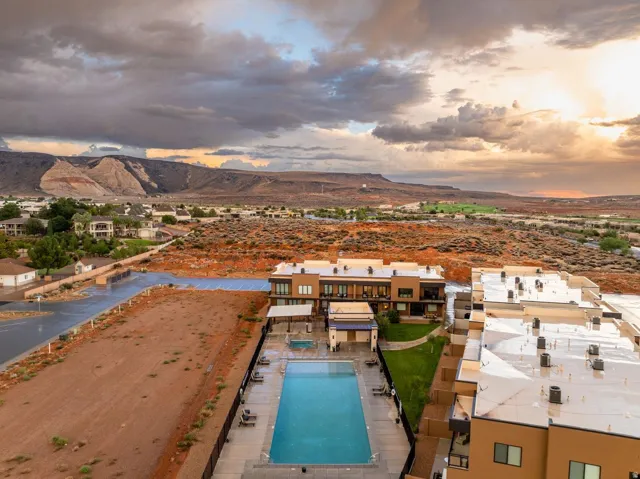 Community pool with integrated spa, surrounding paved deck, and adjacent green space