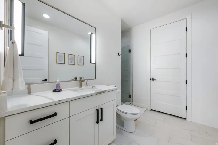 White vanity with a light-toned countertop, rectangular undermount sink, and brushed nickel faucet
