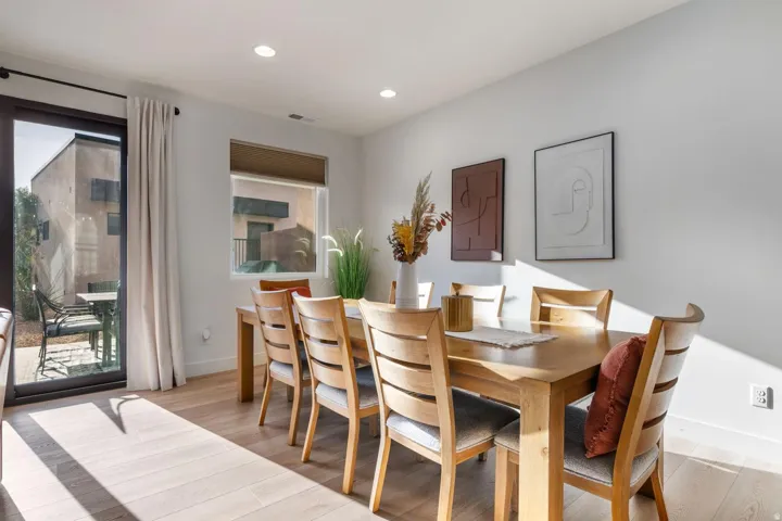 Light wood-finish flooring, recessed lighting, and a large window with roller shades
