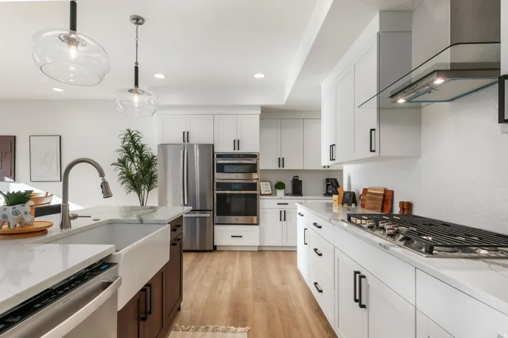 Modern kitchen featuring white cabinetry, stainless steel appliances, a gas range, a farmhouse sink, and wood-finish flooring