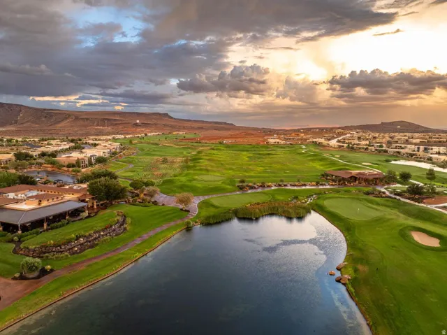 Expansive golf course setting featuring a water hazard, landscaped greens, and surrounding residential development with distant mountains