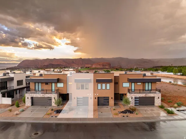 Modern architectural design featuring flat roofs, stucco siding, stone accents, and integrated garages