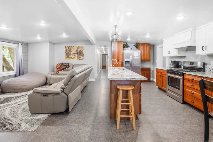 Open-concept living space featuring recessed lighting, a kitchen island with stone countertop, stainless steel appliances, and a window with exterior visibility