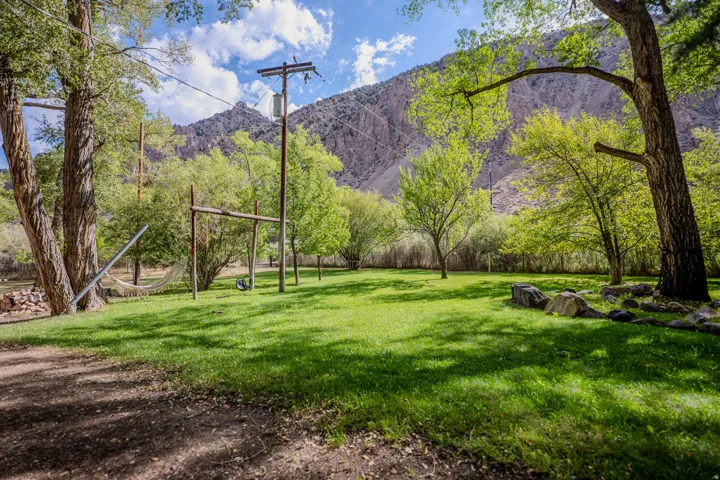Expansive lawn with mature shade trees and natural mountain backdrop