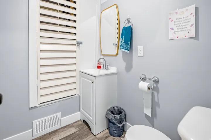 White vanity with integrated sink, chrome-finish faucet, and wood-finish flooring