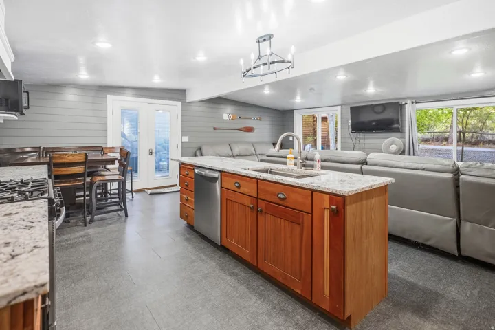 Kitchen island with integrated sink, stainless steel dishwasher, and wood cabinetry