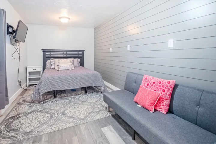 Wood-finish flooring, accent wall with horizontal paneling, and a flush mount ceiling light
