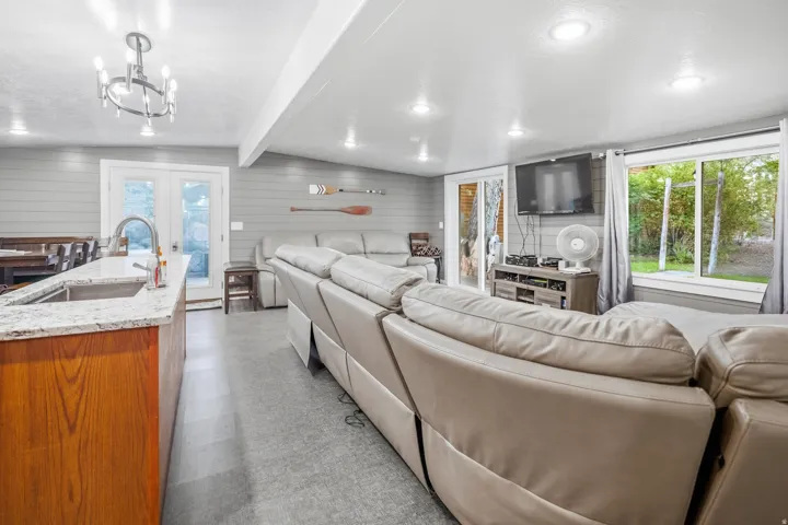 Open living area with recessed lighting, shiplap wall accents, granite-style countertops, wood-finish cabinetry, and French doors
