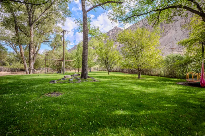 Expansive green lawn surrounded by mature trees, featuring a distant mountain backdrop