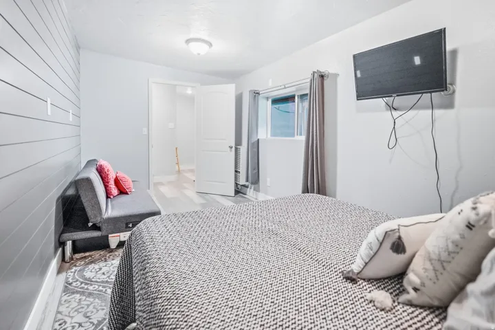 Gray wood-finish flooring, shiplap accent wall, white interior door, and window with curtains