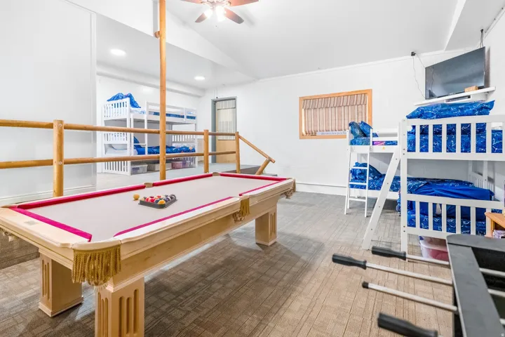 Large recreational space featuring a pool table with red felt, wood-look flooring, multiple built-in bunk beds, and recessed lighting