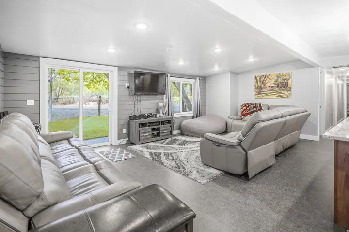 Recessed lighting illuminates this space featuring a sliding glass door, a horizontal plank accent wall, and durable flooring