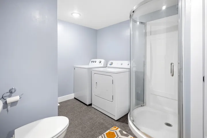 Compact bathroom featuring a curved glass shower enclosure, white toilet, and recessed lighting
