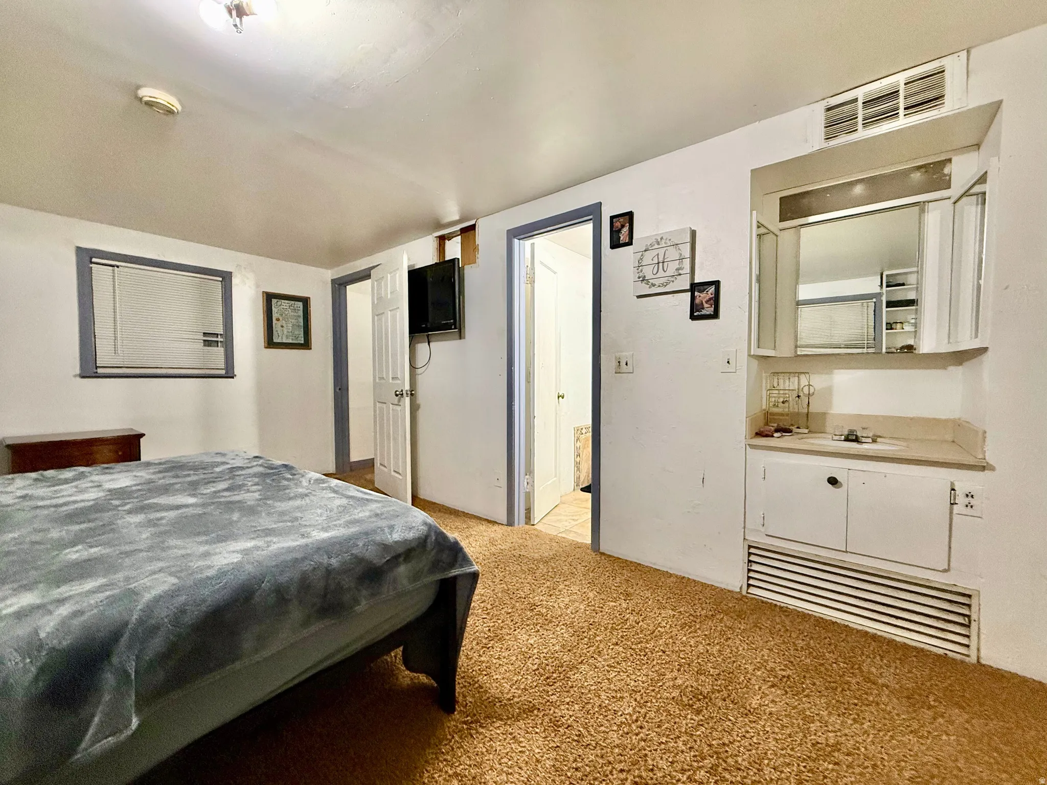 Built-in vanity area with mirror and storage, wall-mounted television, and wood-finish flooring