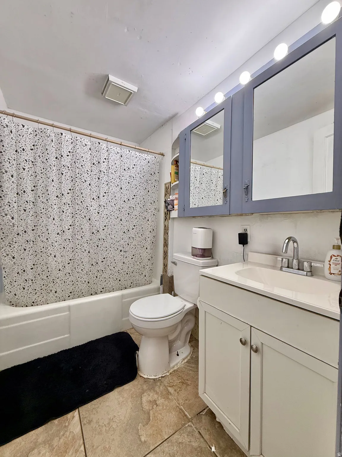 Tile flooring, white vanity with integrated sink, chrome-finish faucet, built-in medicine cabinet with mirror, bathtub with shower
