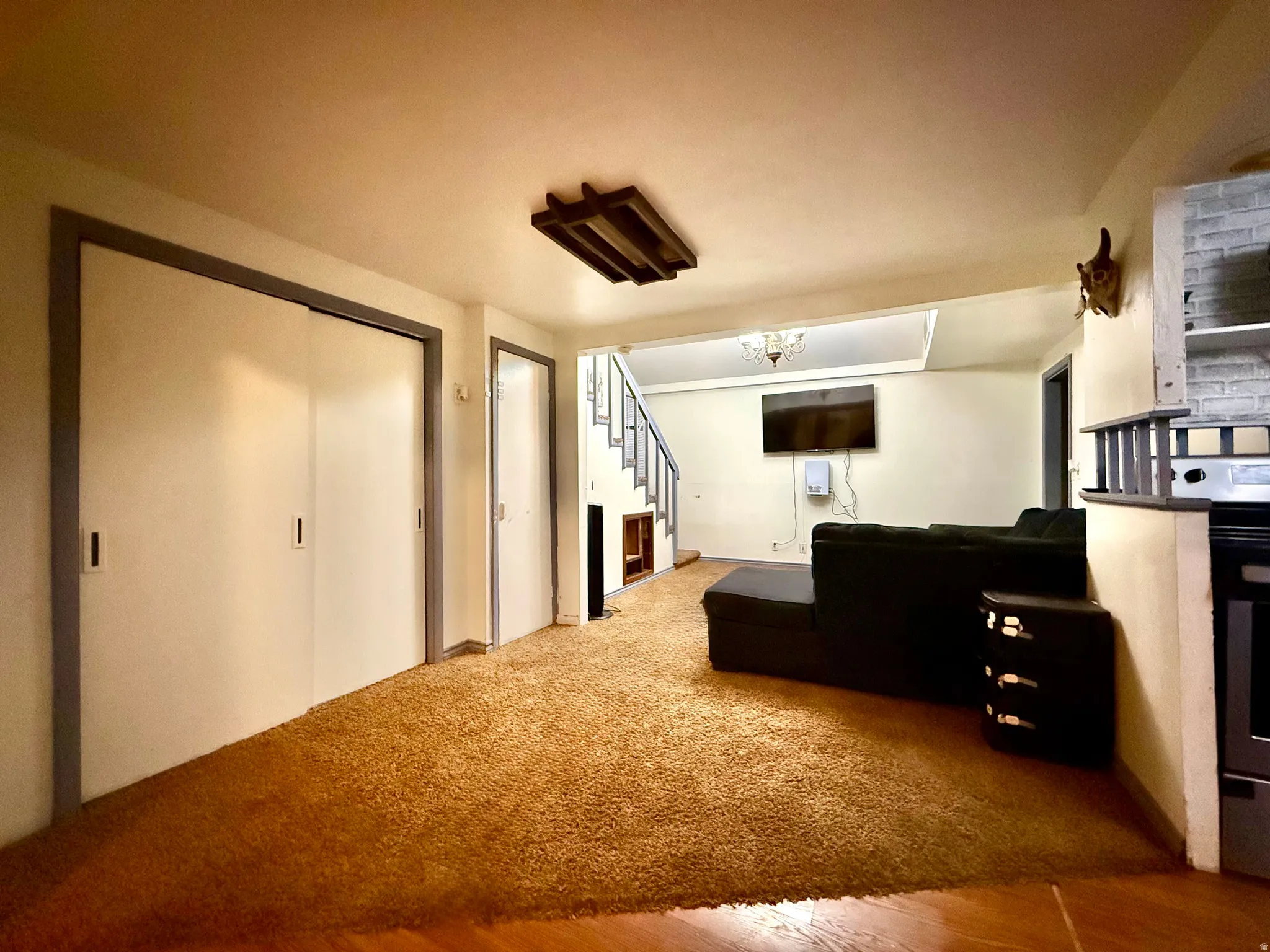 Carpeted floor with wood-finish flooring, built-in shelving, and a prominent staircase