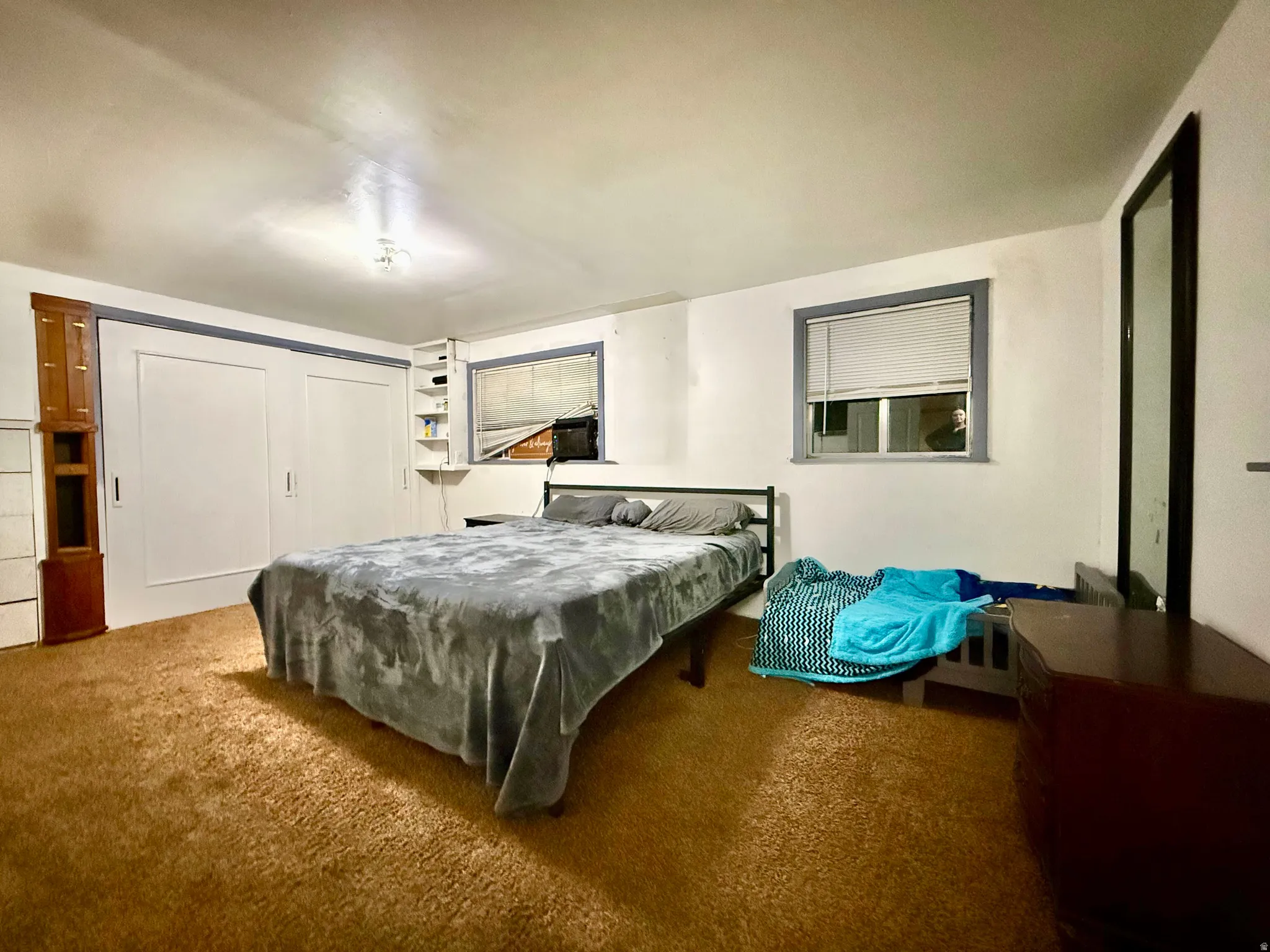 Built-in shelving, two windows with blinds, and wall-to-wall carpeting