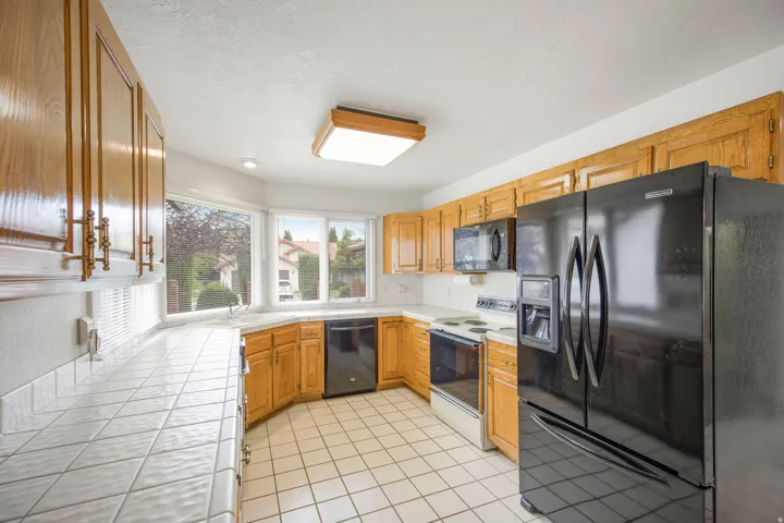 Kitchen featuring wood cabinetry, white tile countertops, white tile backsplash, an integrated sink, and white tile flooring