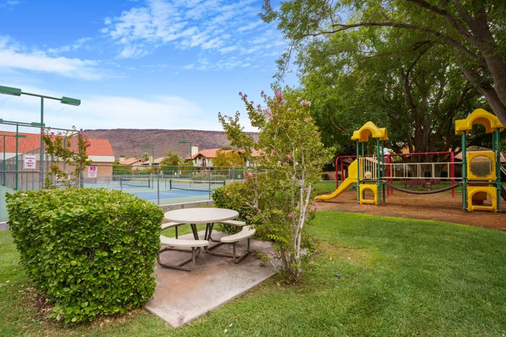 Community tennis courts, playground structure, picnic area with concrete pad, and distant mountain backdrop